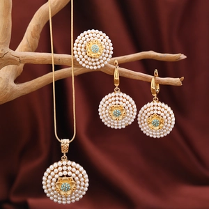 Detailansicht des goldenen Schmucksets mit weißen Perlen und blauen Perlen auf Seide