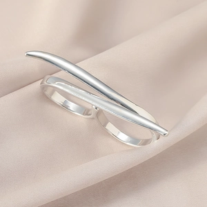 Detailansicht eines polierten silbernen Doppel-Fingerrings auf Champagner-Satin-Hintergrund