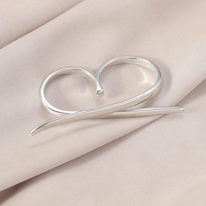 Detailansicht eines abstrakten Herzrings aus Silber auf elegantem Seidenstoffhintergrund