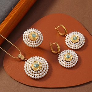 Detail eines goldenen Schmucksets mit weißen Perlen und türkisfarbenen Steinen