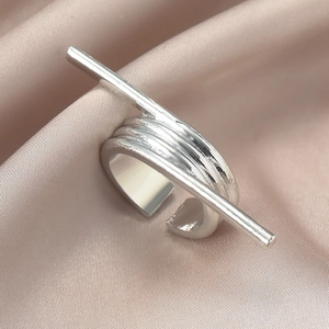 Detailaufnahme eines silbernen Rings mit unregelmäßigen Linien auf Champagner-Satin