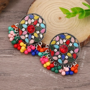 Detalle de pendientes bohemios con cuentas coloridas y diseño de disco de plata retro