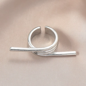 Nahaufnahme eines silbernen Knotenrings mit Metalltextur auf Champagner-Seidenstoff