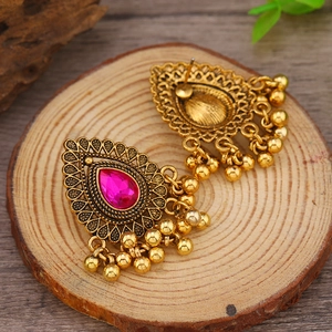 Detalle de pendientes vintage con cristal rosa y gotas de metal dorado colgantes