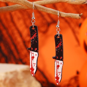 Boucles d'oreilles hachoir ensanglanté pour Halloween sur branche avec fond orange festif