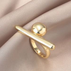 Artistischer goldener geometrischer Ring mit Zylinder- und Kugeldesign auf Seidenstoff
