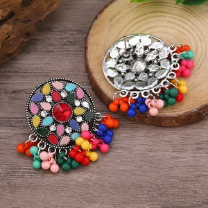 Detalle de pendientes bohemios con cuentas coloridas y acabado en plata antigua