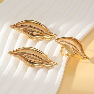 Elegantes goldenes Schmuckset in Blattform mit strukturierten Ringen und Ohrringen auf Ständer