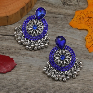 Primer plano de pendientes Jhumka con cristales azul real y filigrana plateada