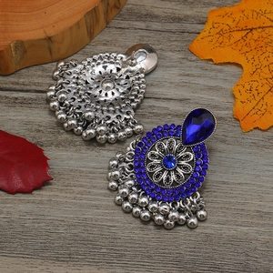Detalle de pendientes vintage bohemios con cristales azules y borlas de metal plateado