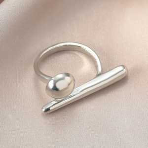 Nahaufnahme eines geometrischen Rings aus poliertem Metall auf champagnerfarbener Seide