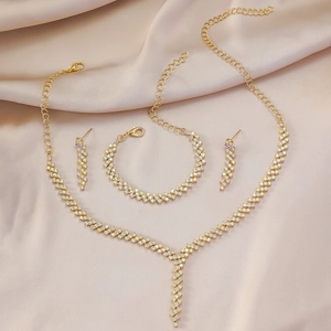 Elegantes goldfarbenes Schmuckset mit irisierenden Strasssteinen auf Seidenstoff