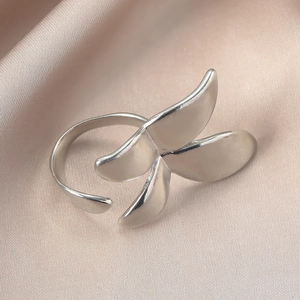 Detail eines silbernen verstellbaren Rings mit Blättermotiv auf Champagner-Satin