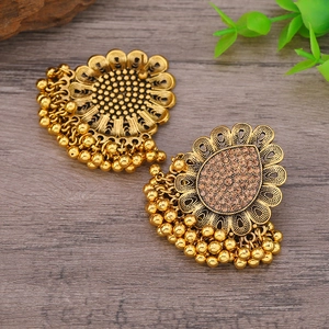 Vista detallada de pendientes étnicos dorados con diseño de girasol y borlas de cuentas