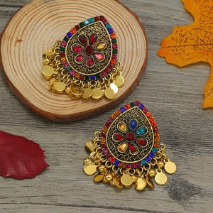 Detalle de pendientes bohemios vintage con cristales de colores y borlas de metal