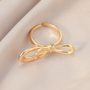 Makro-Detail eines goldenen Schleifenrings auf Champagner-Seide mit glänzender Oberfläche