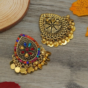 Detalle de pendientes bohemios vintage con pedrería de colores y flecos dorados