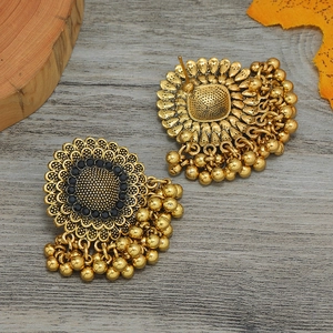 Vista detallada de pendientes bohemios dorados con brillantes negros y borlas de metal