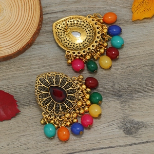 Primer plano de pendientes boho retro con acabado en oro antiguo y cuentas de colores