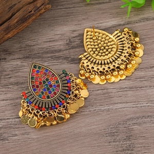 Detalle de pendientes étnicos bohemios con pedrería de colores y monedas doradas