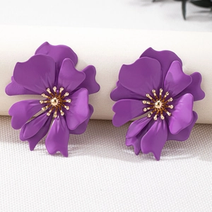 Detail of purple flower stud earrings featuring matte petals and golden textured centers