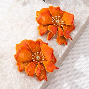 Detailed view of orange gradient enamel flower earrings with golden bead centers on stone
