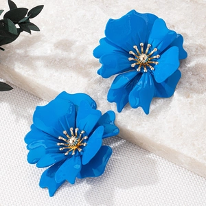 Detailed close-up of blue floral petal earrings with golden stamen on marble background