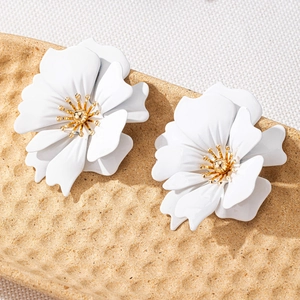 Detail showing elegant white floral earrings with layered petals and golden pistils