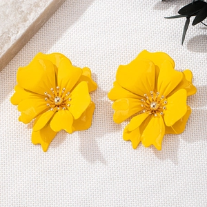 Detailed close-up of bright yellow layered flower earrings on elegant fabric
