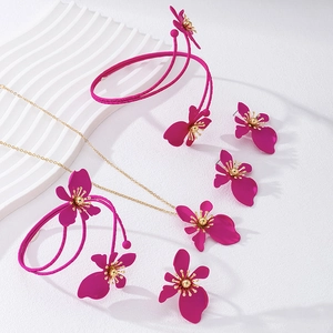 Dettaglio del set di gioielli floreali con fiori in smalto rosa e finiture dorate lucide