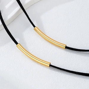 Dettaglio macro del choker in velluto nero con pendenti tubolari dorati lucidi a specchio