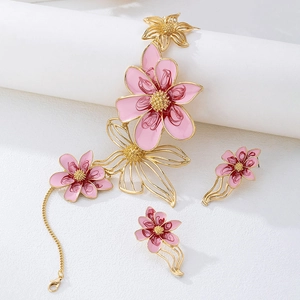 Detalle de un juego de joyas de flores en esmalte rosa con pétalos dorados y textura