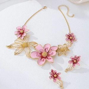 Vista detallada del collar y pendientes florales con esmalte rosa sobre base de metal dorado