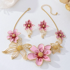 Conjunto de joyas con flores de esmalte rosa, collar y pendientes en fondo de mármol