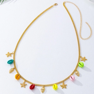 Détail de la chaîne de taille dorée avec coquillages colorés et breloques étoile