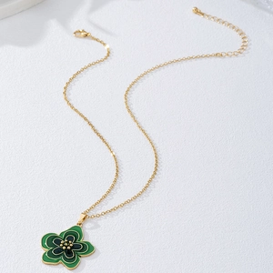 Détail du pendentif fleur en émail vert avec sa chaîne dorée et son fermoir mousqueton