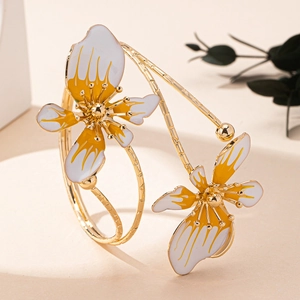 Dettaglio ravvicinato di un bracciale a fascia dorato con fiori in smalto bianco e giallo