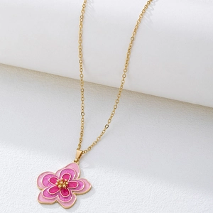 Détail d'un collier en chaîne dorée avec un pendentif fleur en émail rose dégradé élégant