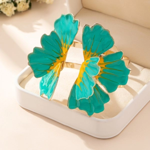 Close-up of a floral open bangle with teal enamel petals in a beige jewelry box