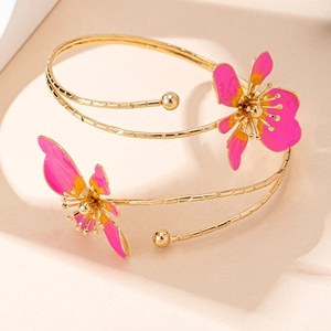 Dettaglio macro del bracciale dorato con fiori in smalto rosa e giallo vivace