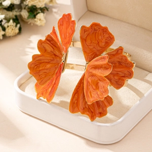 Detailed macro view of large orange marble petal bangle with gold plated metal finish