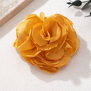 Elegant yellow fabric rose brooch handcrafted with layered chiffon on a textured background