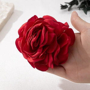 Detailed view of a large deep red fabric rose brooch with realistic layered petals