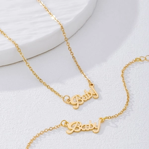 Detailed close-up of golden Baby letter pendant necklace and bracelet jewelry set