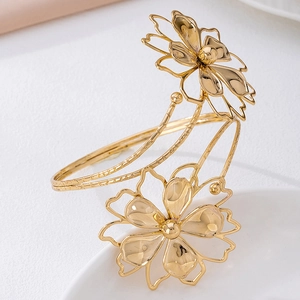 Detalle de brazalete de brazo dorado con flores pulidas y caladas para mujer moderna
