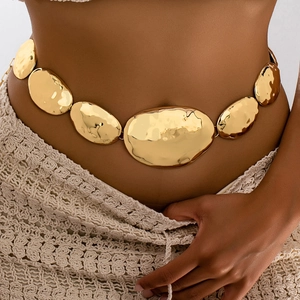 Close-up of golden irregular geometric waist chain with handcrafted hammered metal texture