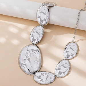 Macro detail of irregular pebble-shaped silver metal waist chain with hammered texture