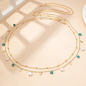 Gold double-layered waist chain with star pendants and turquoise stones on beige surface