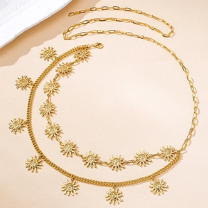 Detail of bohemian gold multi-layer waist chain with sun face charms on a beige surface