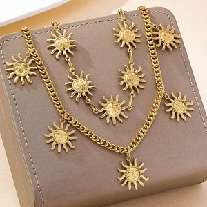 Detail of double-layer gold chain with vintage sun face pendants on gray leather